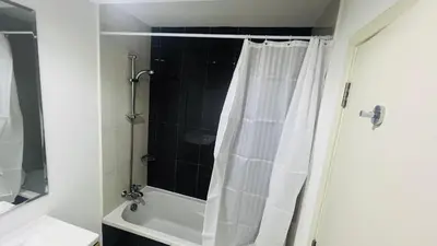 a bathroom with a shower with a white shower curtain at Newly Furnished bright and cozy studio apartment - Damac Hills in Dubai