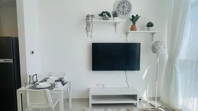 a living room with a tv on a white wall at Newly Furnished bright and cozy studio apartment - Damac Hills in Dubai