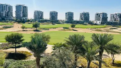 a view of a golf course with palm trees and buildings at Newly Furnished bright and cozy studio apartment - Damac Hills in Dubai