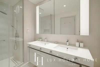a bathroom with a sink and a shower and a mirror at LUX The Luxury Sunrise Beachfront Suite 1 in Dubai