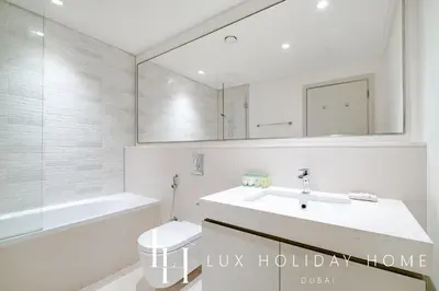 a white bathroom with a sink and a mirror at LUX The Luxury Sunrise Beachfront Suite 1 in Dubai