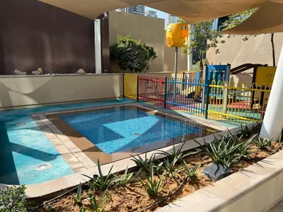 a swimming pool with a fence next to a playground at Luxurious 3BR Maid room 33rd Floor Marina Gate in Dubai