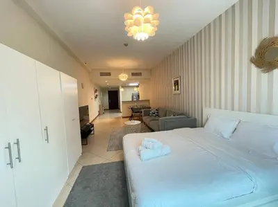 a bedroom with a large white bed and a living room at Amazing Largest Studio in Marina Next to Metro - Central Location in Dubai