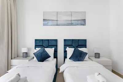 a bedroom with two beds with blue pillows at StoneTree - Marina Gate 2 BR - Prime location in Dubai