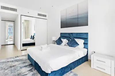 a bedroom with a large bed with a blue headboard at StoneTree - Marina Gate 2 BR - Prime location in Dubai