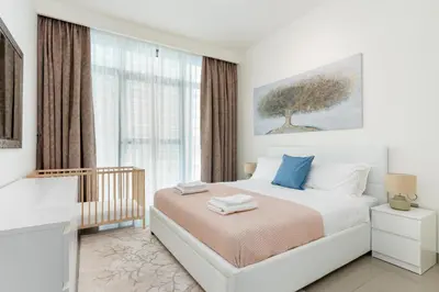 a white bedroom with a bed and a window at Vacay Lettings - Private Beach Access -Emaar Beachfront in Dubai