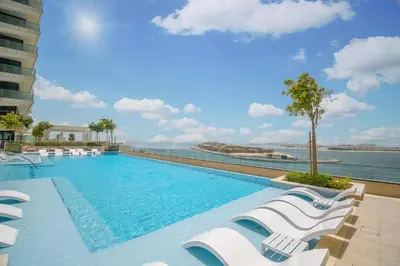 a swimming pool with lounge chairs and the water at Vacay Lettings - Private Beach Access -Emaar Beachfront in Dubai