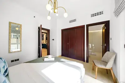 a bedroom with a bed and a chair and a mirror at Classy Design 2BR in Old Town w/ Burj Khalifa View in Dubai