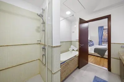a bathroom with a shower and a tub and a bed at Contemporary & Roomy 2BR with Burj Khalifa view in Dubai