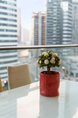 a red vase with flowers on a table in front of a window at Contemporary & Roomy 2BR with Burj Khalifa view in Dubai