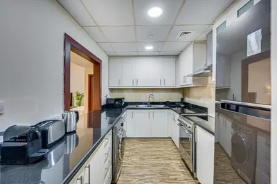 a kitchen with white cabinets and black counter tops at New sea view Rimal 2BD in front of the beach in Dubai