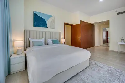 a large bedroom with a large white bed with blue pillows at New sea view Rimal 2BD in front of the beach in Dubai