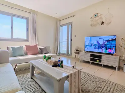 a living room with a couch and a tv at Stylish 1 BR with sea view - Sunset view in Dubai