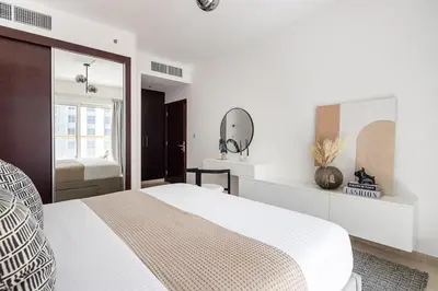 a white bedroom with a bed and a mirror at Frank Porter - Elite Residence in Dubai
