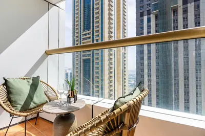 a balcony with two wicker chairs and a table in front of a window at Frank Porter - Elite Residence in Dubai