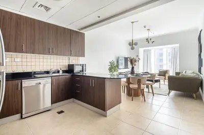 a kitchen with wooden cabinets and a dining room at Frank Porter - Elite Residence in Dubai