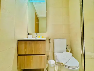 a bathroom with a toilet and a sink and a mirror at Venduras - Skyline View Farhad Azizi Residence Al Jaddaf in Dubai