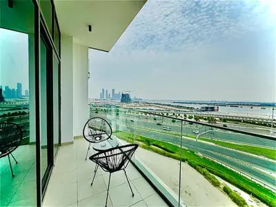 a balcony with two chairs and a view of a highway at Venduras - Skyline View Farhad Azizi Residence Al Jaddaf in Dubai