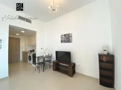 a living room with a tv and a table with chairs at Mira Holiday Homes - Serviced Studio in Una Apartment in Dubai