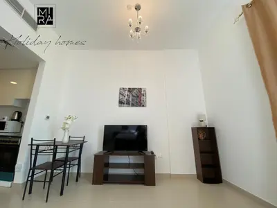 a living room with a tv and a table and chairs at Mira Holiday Homes - Serviced Studio in Una Apartment in Dubai