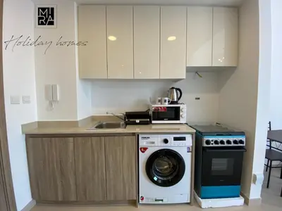 a kitchen with a washing machine and a microwave at Mira Holiday Homes - Serviced Studio in Una Apartment in Dubai