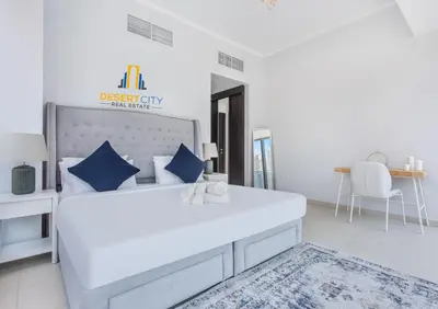 a white bedroom with a large white bed with blue pillows at One Bed in Dubai Marina with Marina Views, Hosted by Desert City Stays in Dubai