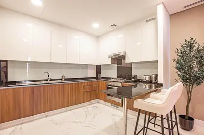 a kitchen with white cabinets and a black counter top at Daniels Canal View 1BR at J One Business Bay in Dubai
