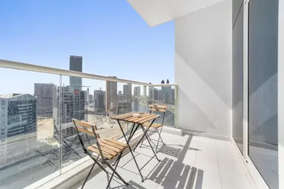 a balcony with two chairs and a table on a building at Elegant 1BR - Spacious & Luxury - Canal View in Dubai