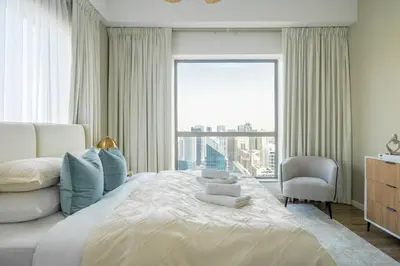 a bedroom with a large bed with a chair and a window at GuestReady - Modern and luxe near JBR Beach in Dubai