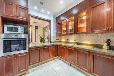a large kitchen with wooden cabinets and appliances at Manzil - Cozy 2BR Penthouse with Private Terrace and Full Burj View in Downtown in Dubai