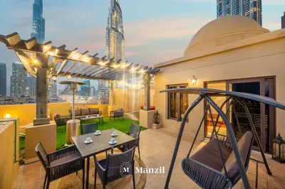 a rooftop patio with a table and chairs and a swing at Manzil - Cozy 2BR Penthouse with Private Terrace and Full Burj View in Downtown in Dubai