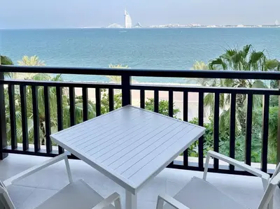a white table and chairs on a balcony with the ocean at Upgraded Gorgeous 1BR at 5 Star Resort in Dubai