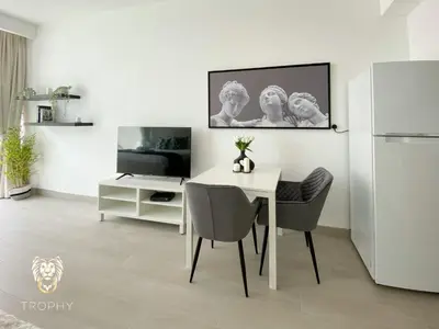 a white dining room with a table and a refrigerator at Stylish Studio Apartment in JVC with Contemporary in Dubai