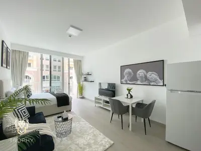 a white room with a bed and a table with chairs at Stylish Studio Apartment in JVC with Contemporary in Dubai