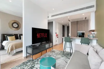 a living room with a couch and a kitchen with a bed at Vacay Lettings - Suite room in Marina gate, Jumeirah living in Dubai