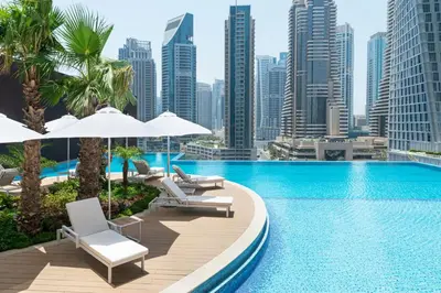 a pool with chairs and umbrellas and a city skyline at Vacay Lettings - Suite room in Marina gate, Jumeirah living in Dubai