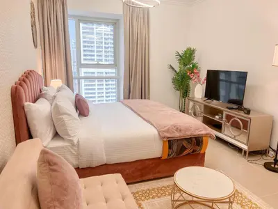 a bedroom with a large bed and a television at Cosmos Living Cozy Studio Near Dubai Marina in Dubai