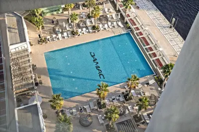an overhead view of a swimming pool with chairs and palm trees at ALiving Modern Studio I Canal View I DAMAC Maison Prive A- 1102 in Dubai