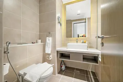 a bathroom with a sink and a toilet and a mirror at ALiving Cozy & Modern Studio I DAMAC Maison Prive, Business Bay -302 in Dubai