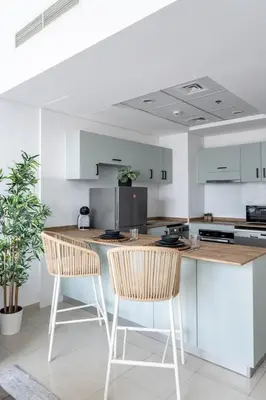 a white kitchen with two chairs and a counter at GuestReady - Exquisite getaway with Marina views in Dubai