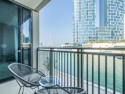 a balcony with two chairs and a view of the water at Bright and Splendid 1BR with Marina View in Dubai