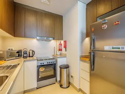 a kitchen with wooden cabinets and a stainless steel refrigerator at Marvelous 1BR with Beautiful Marina View in Dubai