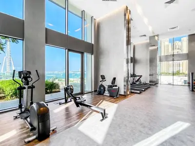 a gym with cardio machines and large windows at Gorgeous 1 BR with Private Terrace - Marina View in Dubai