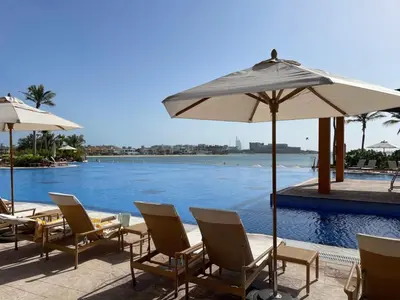 a group of chairs and umbrellas next to a swimming pool at 2 BD Tiara Palm Views, Beach & Pool, Amazing views of the Palm in Dubai