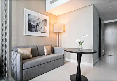 a living room with a couch and a table at ALiving Stylish Studio with Balcony I Partial Burj Khalifa View I DAMAC Maison Prive B-1315 in Dubai