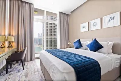 a hotel room with a bed and a desk and a window at ALiving Stylish Studio with Balcony I Partial Burj Khalifa View I DAMAC Maison Prive B-1315 in Dubai
