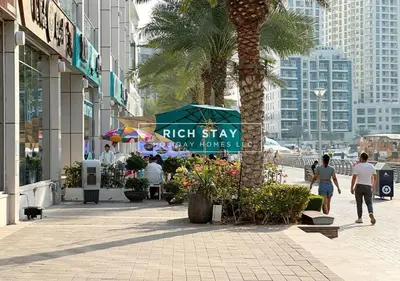 people walking down a sidewalk in a city with a palm tree at Grande 3BR in Stella Maris, Sea View, Dubai Marina in Dubai
