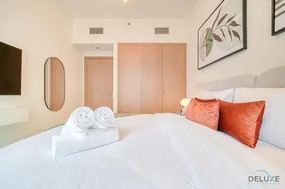 a bedroom with a large white bed with orange pillows at Classic 1BR at Harbour Views Tower 1 by Deluxe Holiday Homes in Dubai