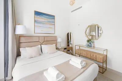 a white bedroom with a large bed and a mirror at Perfect 1 BR for Family Stay - Close to Downtown in Dubai