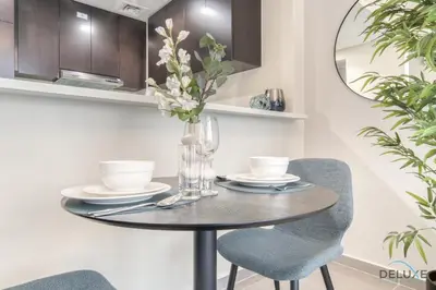 a dining room table with two chairs and a circular mirror at Soothing 1BR at Merano Business Bay by Deluxe Holiday Homes in Dubai